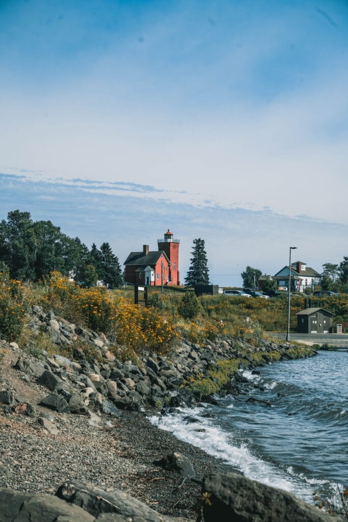 The Two Harbors lighthouse above the Lake Superior shore, wildflowers in the foreground