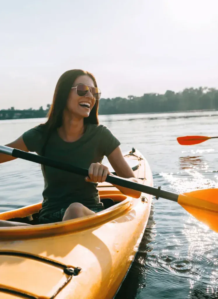 A woman kayaking on calm water in low evening light